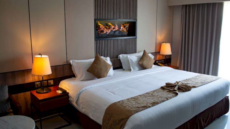 A neatly made hotel room with a large bed, two nightstands, and a TV mounted on the wall.