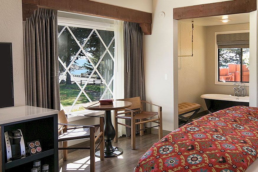A wide view of a hotel room with a bed, table, chairs, and window
