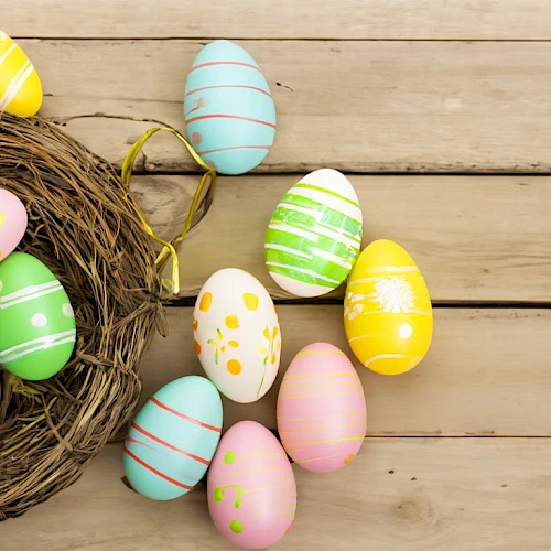 Colorful Easter eggs in a nest on a wooden surface, with pastel patterns and polka dots, bright and cheerful.